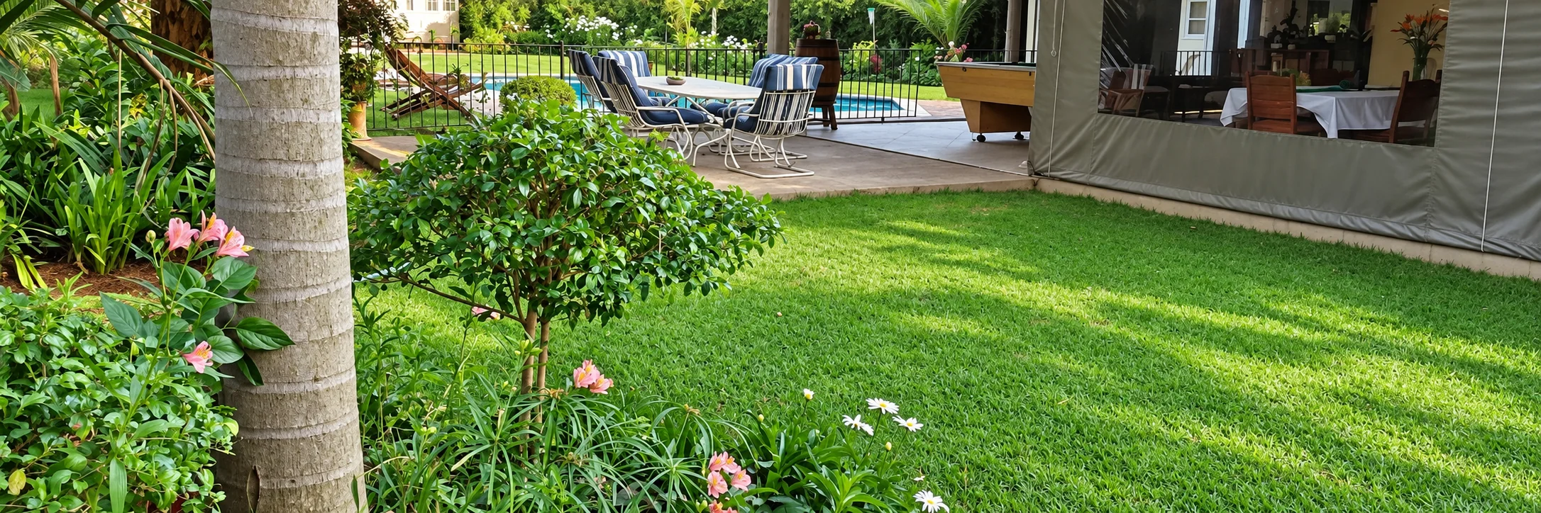 A shaded garden patio with striped chairs, a pool table and a view of the swimming pool